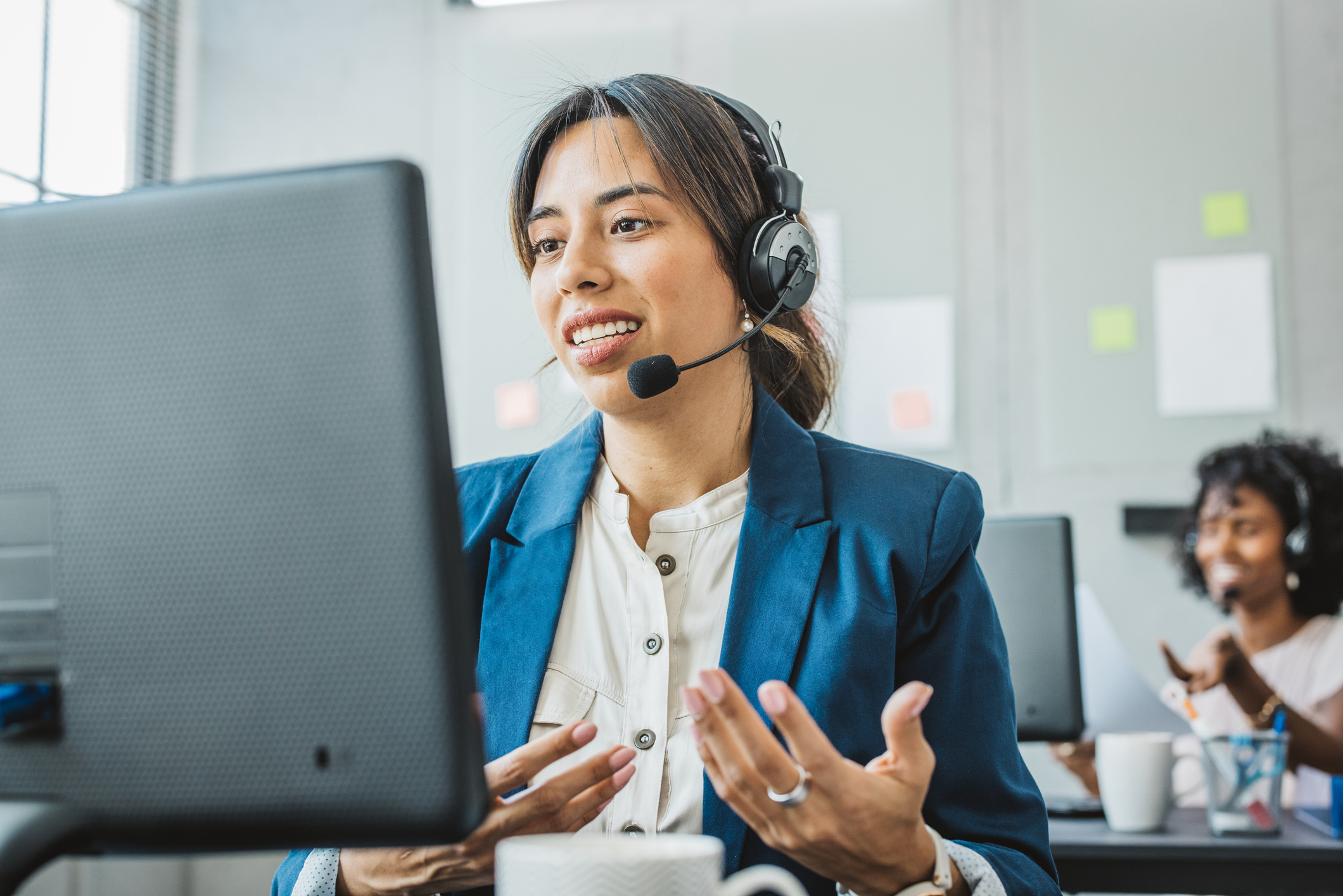 Friendly woman in call center service talking with costumers by headset.