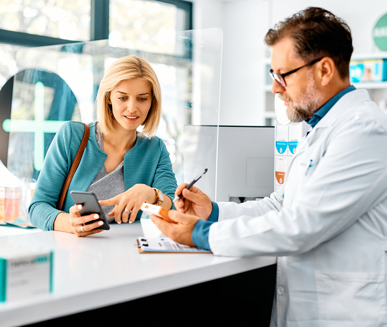 Young female customer speaks with a male pharmacist about a prescription that she is filling at the drug store.