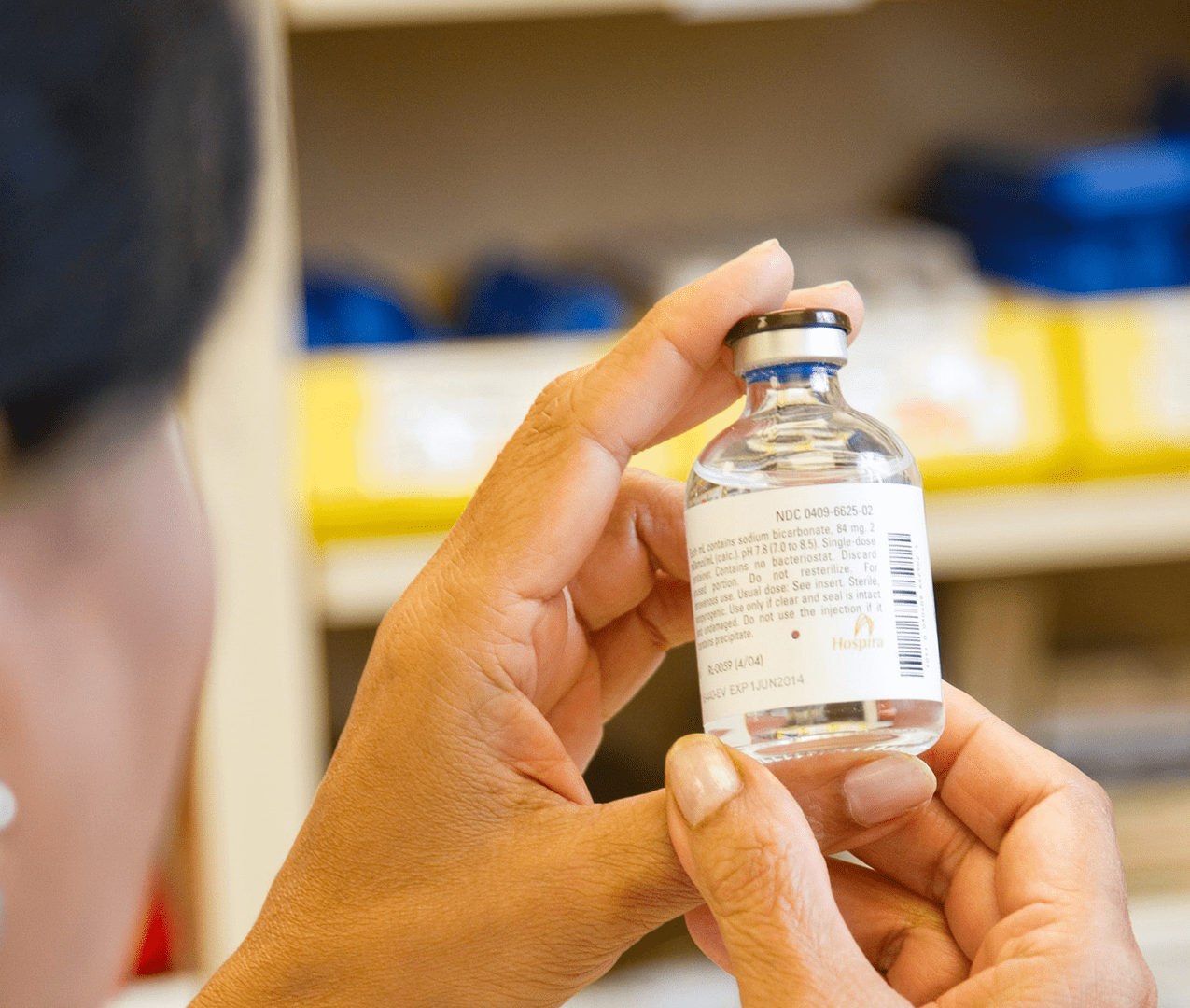 Pharmacist examines the NDC label on a vaccine vial.