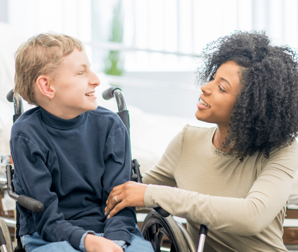 Young woman speaking to boy in wheelchair.