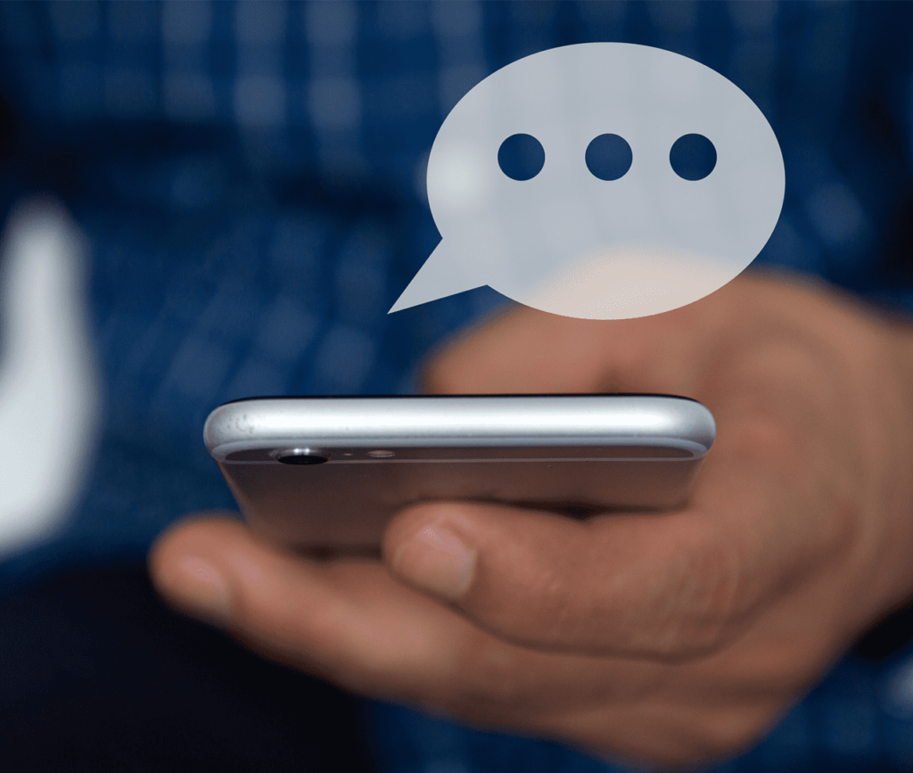 Close up of man holding cellphone with a chat bubble popping out of the screen.