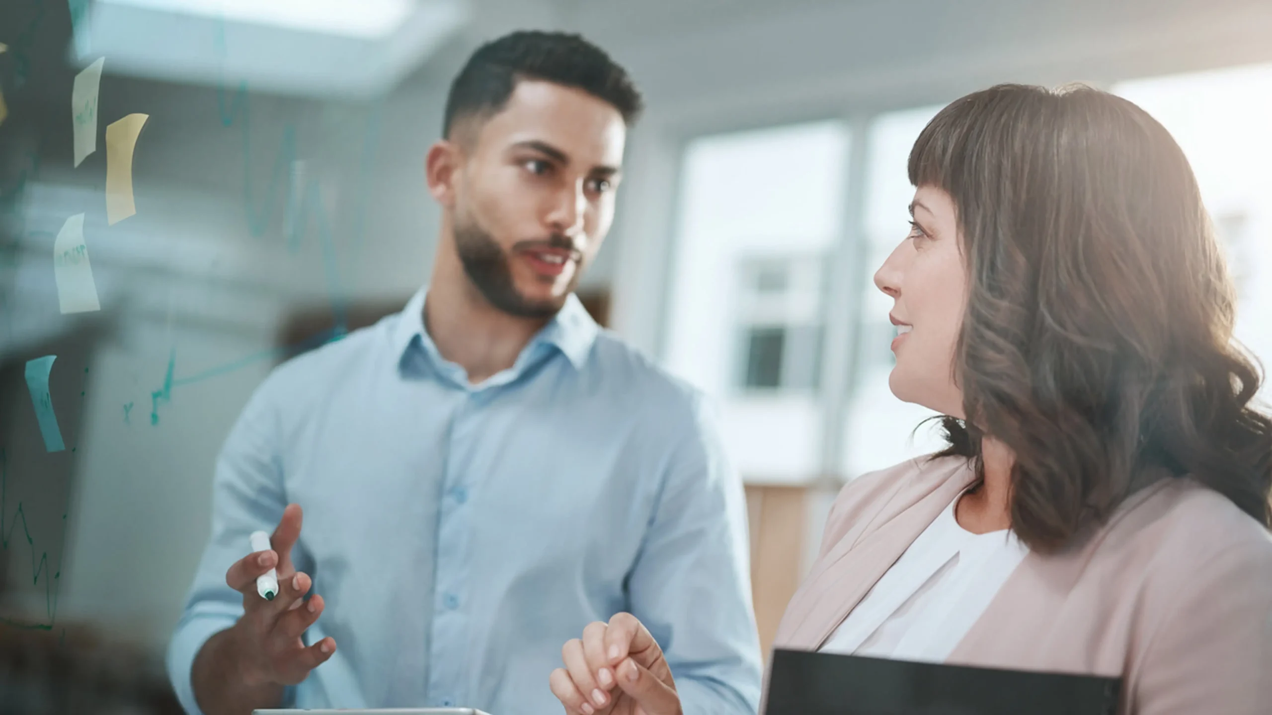People discussing using glass whiteboard and post-it notes